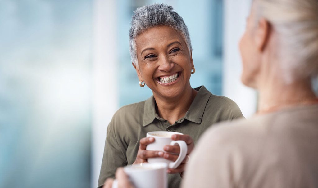 Two senior women drinking coffee and laughing